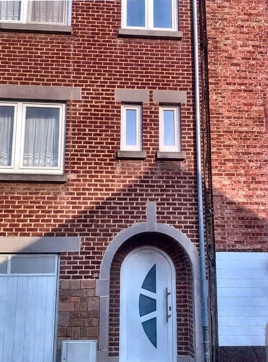 Façade en brique avec porte d'entrée cintrée blanche